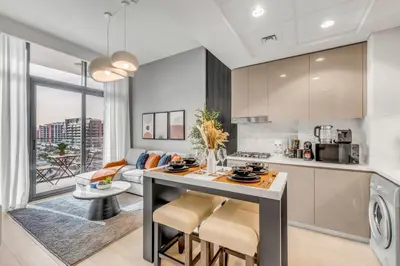 a kitchen and living room with a table and chairs at 1BR Royal Bedroom with Pool & Gym Free in Dubai