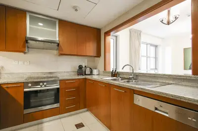 a kitchen with wooden cabinets and a sink and a window at Stylish 1BR in Downtown - 5 Min to Burj & Mall in Dubai