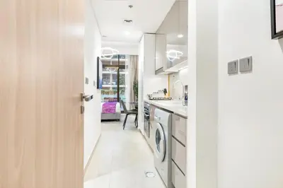 a white kitchen with a washer and dryer in it at Elite Apartments in Meydan in Dubai