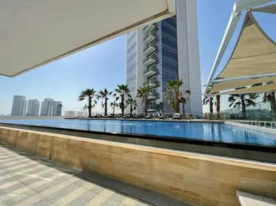 a swimming pool with palm trees and a tall building at PVH - Serene Studio with Skyline View - Carson B in Dubai