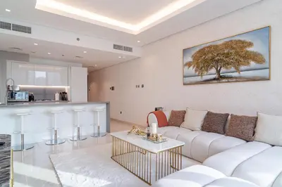 a living room with a white couch and a tree on the wall at Luxury 1 BR At The Sterling in Dubai