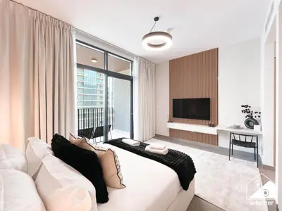 a living room with a white couch and a large window at Comfort Studio in Meydan With Gym, Pool & Parking in Dubai
