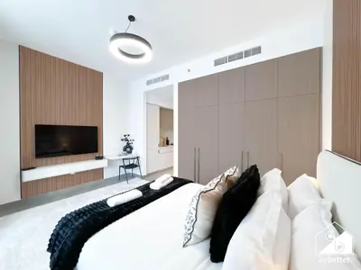 a bedroom with a large white bed with a flat screen tv at Luxury Studio in Meydan With Gym, Pool Access in Dubai
