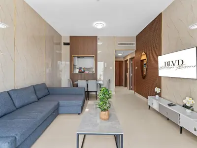 a living room with a blue couch and a table at BLVD - Scenic View Stay with Pool and Gym Access in Dubai