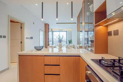 a kitchen with wooden cabinets and a stove top oven at Chic 2BR Flat in Park Lane Dubai in Dubai