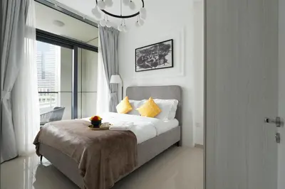 a bedroom with a bed with yellow pillows and a window at KeyRock - Modern 1BR in Zada with Pool & View in Dubai