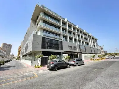 a building with two cars parked in front of it at HAVN - Brand New Studio in Oxford Boulevard, JVC in Dubai