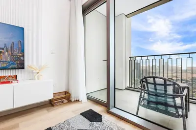 a room with a balcony with a chair and a window at Luxury Skyline View 1BR with Pool, Gym, Parking, Concierge & Near Metro in Dubai