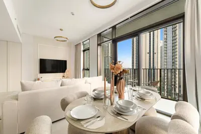 a living room with a white couch and a table and chairs at Prime 2BR Retreat, Creek Harbour Views & Comfort Near Restaurants in Dubai