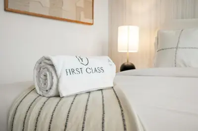 a towel that says first class sitting on a bed at FIRST CLASS 1BR Living Garden Luxury and Comfort in Dubai