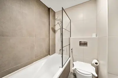 a bathroom with a tub and a toilet and a shower at FIRST CLASS 1BR Living Garden Luxury and Comfort in Dubai