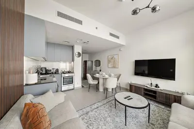 a living room with a couch and a table and a kitchen at FIRST CLASS 1BR Living Garden Luxury and Comfort in Dubai