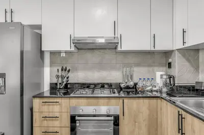 a kitchen with white cabinets and a stove top oven at Brand New Luxury 2 Bedroom in Dubai