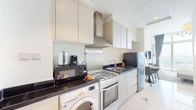 a kitchen with white cabinets and a stove top oven at Carson A - High Rise Cosy Studio with City Views in Dubai
