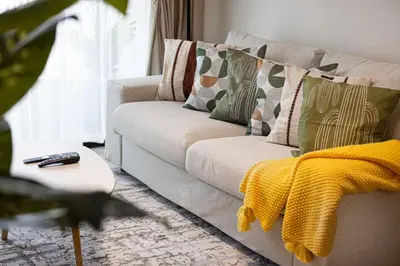 a living room with a couch with pillows and a yellow blanket at Luxury Stay in JVC in Dubai