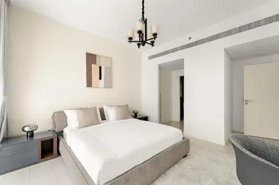 a white bedroom with a large bed and a chair at Sea View 2BR Apartment With Private Beach in Dubai