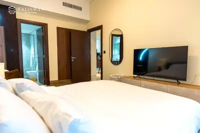 a bedroom with a large bed and a flat screen tv at Elegant 1 BR Apartment in J One Tower in Dubai