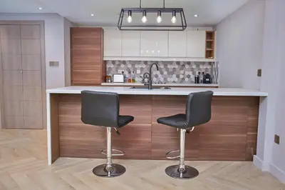 a kitchen with two bar stools and a sink at Vista Downtown Poolside 1BR Walk to Burj Khalifa in Dubai