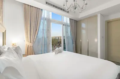a white bedroom with a large white bed and a chandelier at FIRST CLASS VILLA Spacious for Family Getaways in Dubai