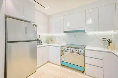 a white kitchen with white cabinets and a refrigerator at PVH - Binghatti Heights - Urban Luxury 3BR in Dubai