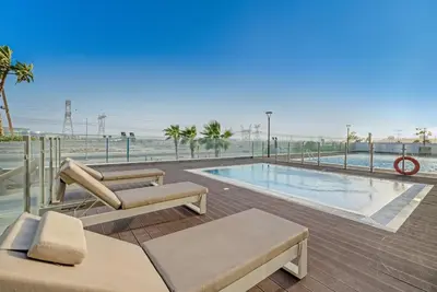 a swimming pool with a view of the ocean at Stylish 1BR with Pool Gym and Parking in Riviera 12 in Dubai