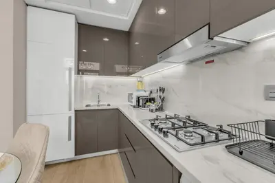 a white kitchen with a stove and a sink at Stylish 1BR with Pool Gym and Parking in Riviera 12 in Dubai