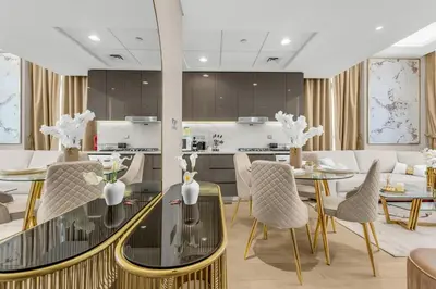 a kitchen and living room with a table and chairs at Stylish 1BR with Pool Gym and Parking in Riviera 12 in Dubai