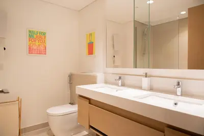a bathroom with a sink and a toilet and a mirror at Homely Creek Harbour Apartment - Direct Park Access in Dubai