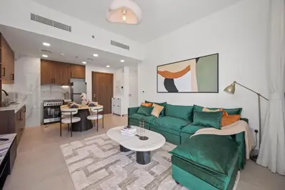 a living room with a green couch and a kitchen at Luxury 1BR Apartment Dubai in Dubai