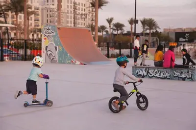 two young children riding scooters in a skate park at Luxury 1BR Apartment Dubai in Dubai