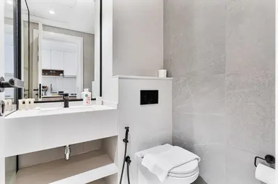 a bathroom with a toilet and a sink and a mirror at Chic Studio APT with Pool & Gym - Near Metro Station in Dubai