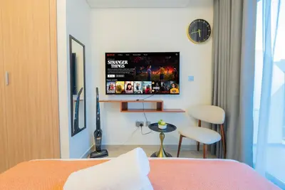 a bedroom with a bed and a table and a clock at Modern Studio Retreat in Dubai in Dubai