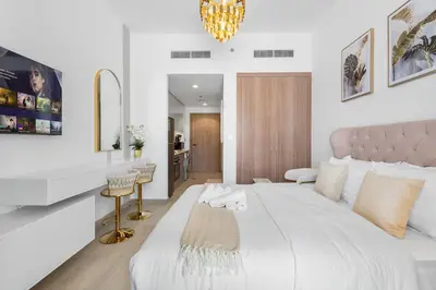 a white bedroom with a large bed and a bathroom at Cozy Downtown Studio Dubai Retreat in Dubai
