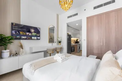 a white bedroom with a large bed and a kitchen at Cozy Downtown Studio Dubai Retreat in Dubai