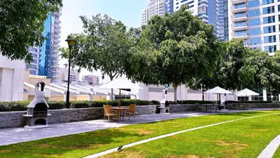a park with chairs and tables and umbrellas at Blakely Tower, Park Island, Dubai Marina - Mint Stay in Dubai