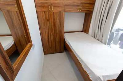 a small room with two beds and wooden cabinets at Al Barsha Hostel for Girls in Dubai