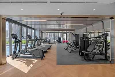 a gym with a row of treadmills and machines at 2BR Guest Favorite Elegant Apartment at Riviera 67 in Dubai