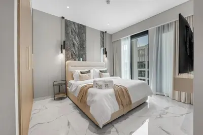 a bedroom with a large bed and a flat screen tv at 2BR Guest Favorite Elegant Apartment at Riviera 67 in Dubai