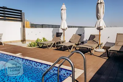 a swimming pool with chairs and umbrellas on a roof at Exclusive 2BR With City View Pool & Gym Access in Dubai