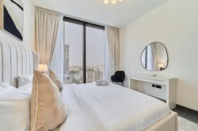 a bedroom with a white bed with a mirror and a window at FAM Living -Bright & Spacious Home in Sobha Hartland in Dubai