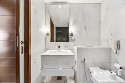 a white bathroom with a sink and a mirror at Kempinski Luxe Studio Burj Khalifa View by Evoke in Dubai