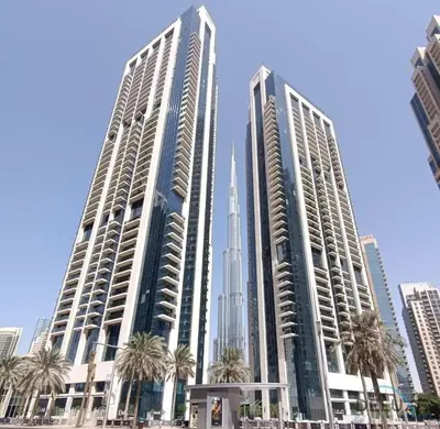 two tall buildings with palm trees in front of a city at Iconic Burj Khalifa, Fountain Views, Luxury 2BR in Sabkhah