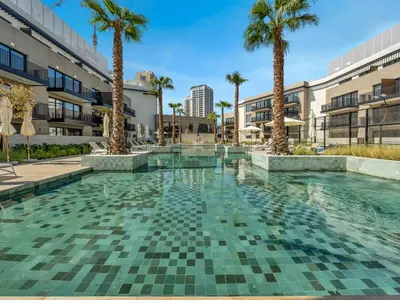 a swimming pool with palm trees and buildings at Luxury Apartment In JVC With Padel Gym Pool Cinema BBQ in Dubai