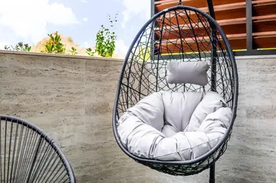a hanging chair with a pillow in a balcony at Luxury Apartment In JVC With Padel Gym Pool Cinema BBQ in Dubai