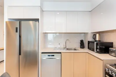 a kitchen with white cabinets and a stainless steel refrigerator at Burj Royale Luxury Burj Khalifa dubai mall downtown city centre in Dubai