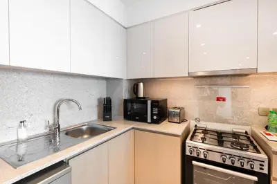 a kitchen with white cabinets and a sink and a stove at Burj Royale Luxury Burj Khalifa dubai mall downtown city centre in Dubai