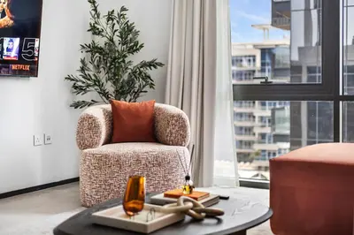 a living room with a chair and a table at Stylish 1BR with Work Desk, Pool and Gym in Dubai
