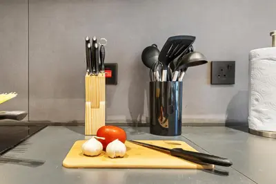 a counter with a cutting board with onions and utensils at Stylish 1BR with Work Desk, Pool and Gym in Dubai