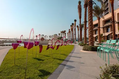 a sidewalk with palm trees and chairs and pink hearts at Harbour Views - Chic Three Bed with Creek Views in Dubai
