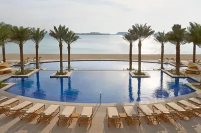 a pool with chairs and palm trees and the beach at Al Dabas - One Bed with Beach Access and Sea View in Dubai
